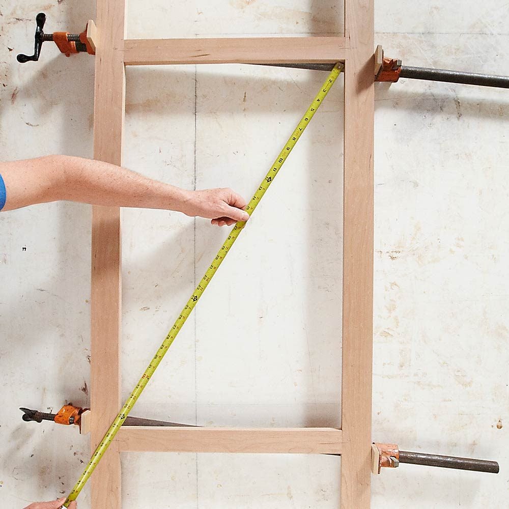 A man squaring a frame with clamps | Construction Pro Tips