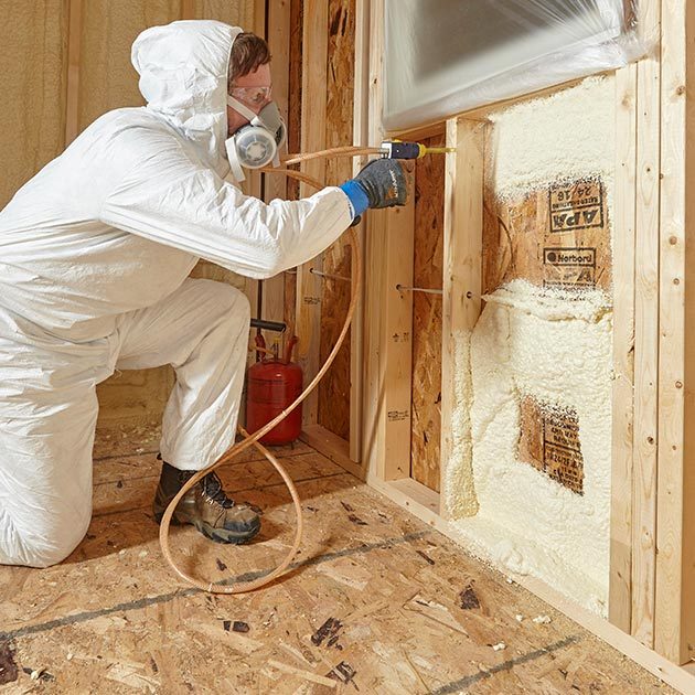 Man spraying insulation into cavity beneath window | Construction Pro Tips