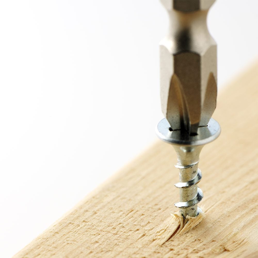 Drill bit driving a screw into a wooden plank | Construction Pro Tips