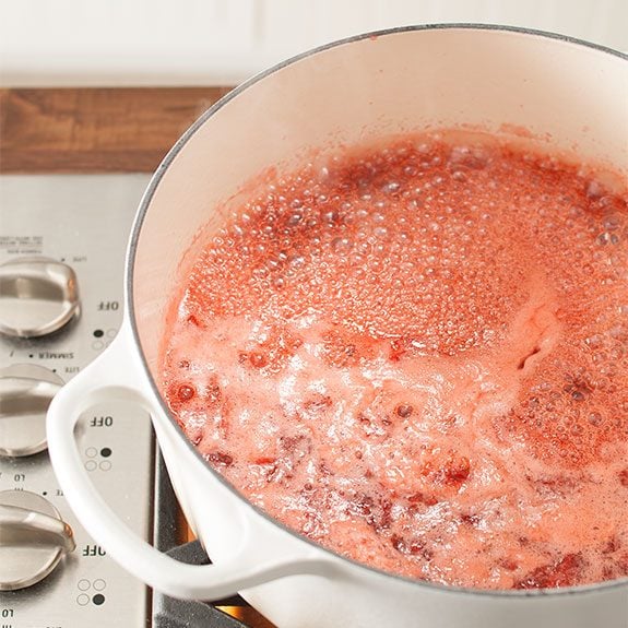 Strawberry jam mixture bubbling in a Dutch oven on the stovetop