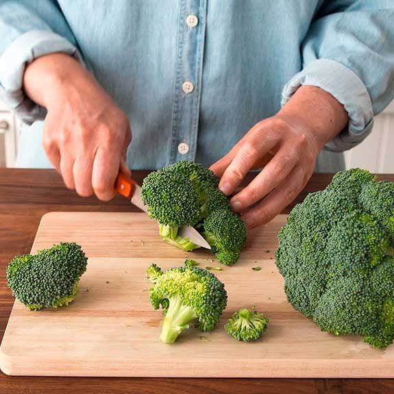 Chopping broccoli on a cutting board.